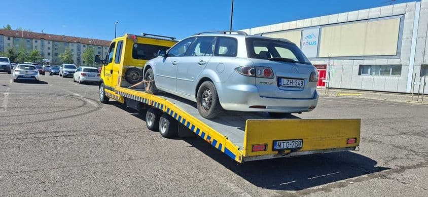 Parkolóban zajló autómentés tréleren.