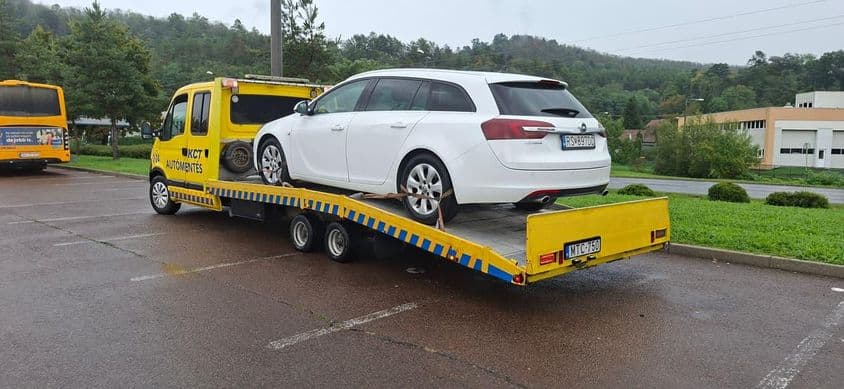 Autómentő tréler szállít sérült kombit.