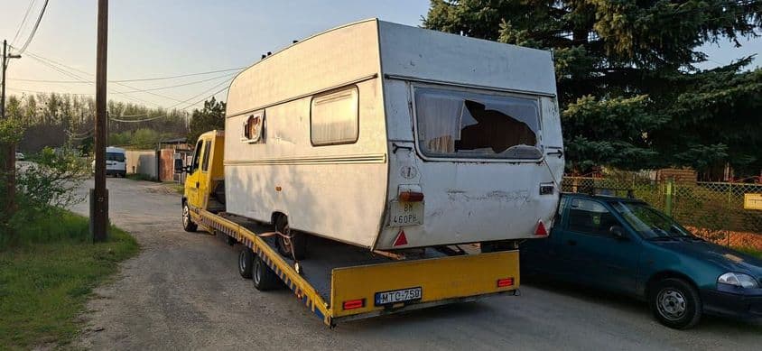 Sérült lakókocsi szállítása tréleren.