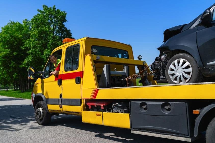 Vontató egy sérült fekete autót szállít